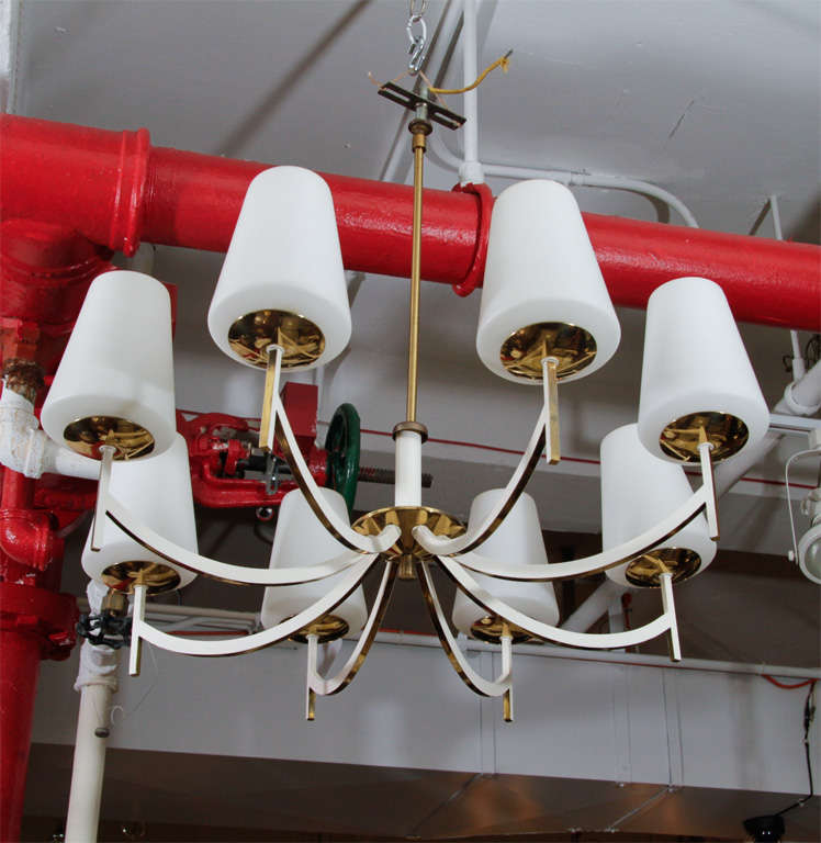 Brass framed chandelier with eight arms and conical matte milk glass shades. Each arm is enameled white on the sides