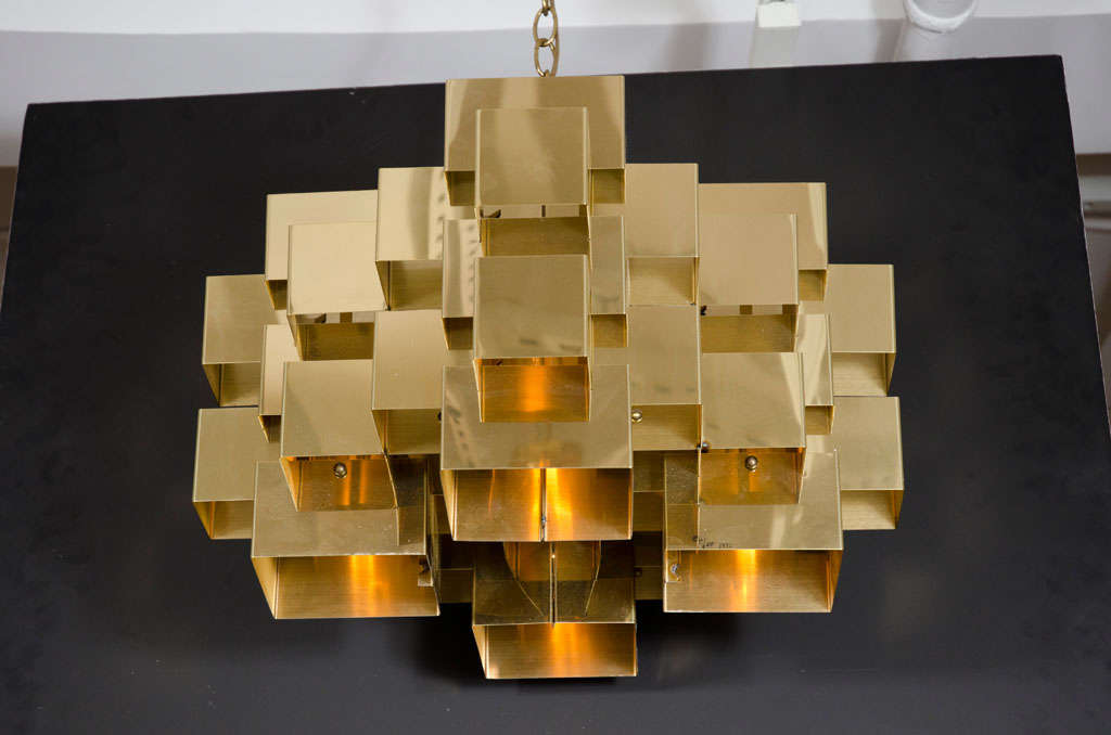 A brass plated steel chandelier with folded interlocking sections, forming an intricate geometric cluster. By Artisan House. Signed [Curtis Jeré]. U.S.A., circa 1970.