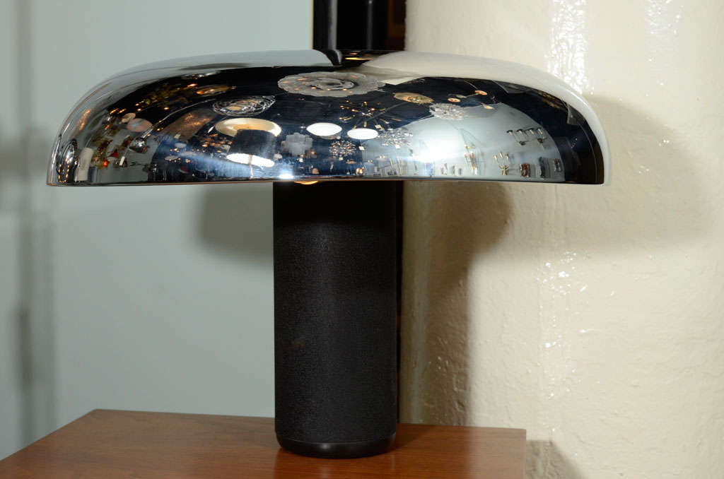 1970s table lamp by Italian lighting company Lumenform. Chromed top shade with ivory enamel underside and black enamel iron column base. The large black plastic disk in the center of the chrome shade is the on/off push button.
Located in Showplace