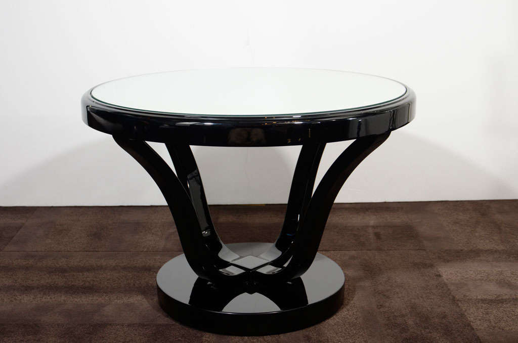 Beautiful gueridon style side table<br />
or occasional table with stylized<br />
base design and round top.<br />
Finished in black lacquer with <br />
a mirrored top.