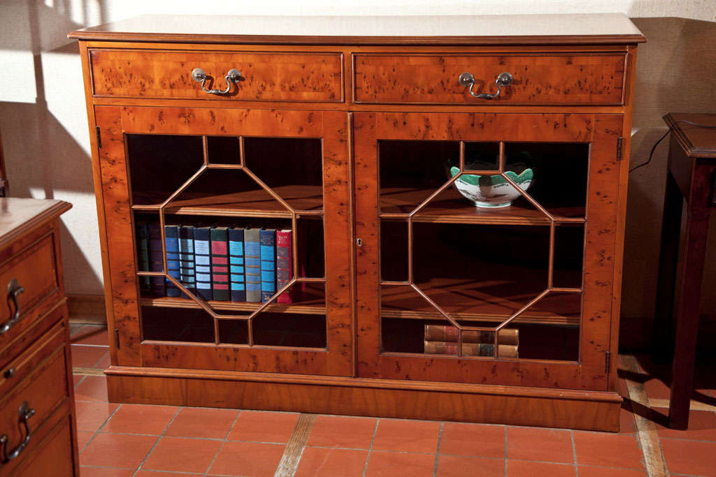Custom crafted for us in England, this bookcase adds the functionality of two drawers.  In yew wood with self banding, it offers enough space for about 100 medium-sized books.  Classic Georgian mullions give the doors interest and the plinth base is