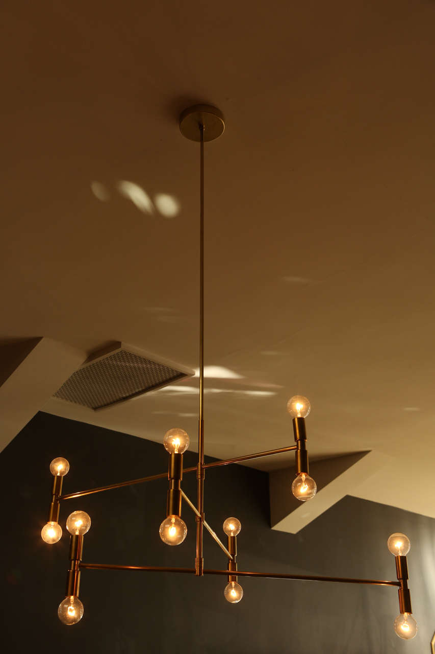 Mid-Century inspired brass pendant fixtures with 12 exposed bulbs paired with linear arms radiating from center rod.
 
Lead time is six to eight weeks.