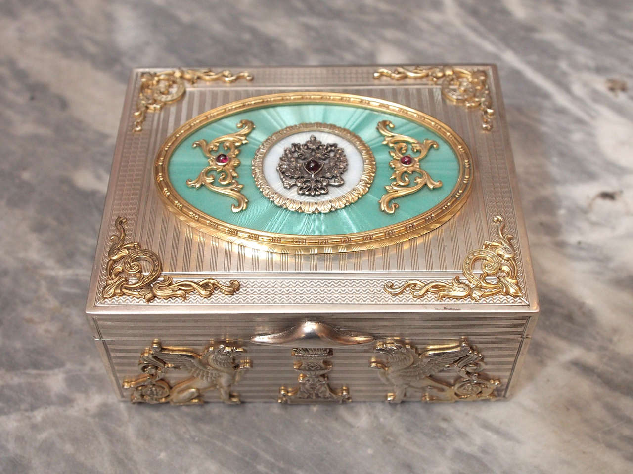 Russian silver box having gold wash appliqué and sphinx design throughout. Jeweled throughout with crown design to top over aqua blue guilloche enamel cartouche.