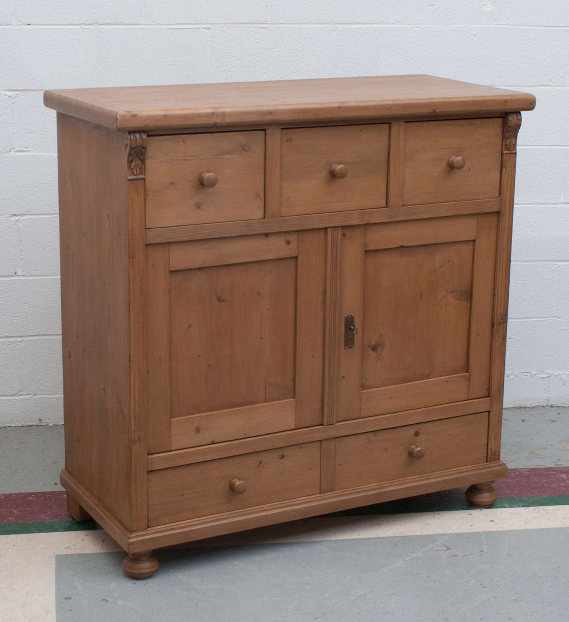 A substantial and well proportioned pine side cupboard featuring five spacious dovetailed drawers, the upper three replacements, and two panelled doors opening to a single central shelf.