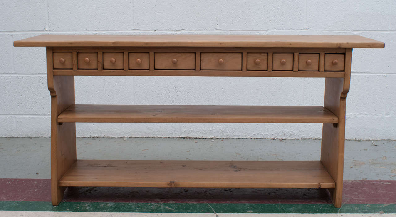 A useful and unusual little water bench with scalloped sides, a central shelf and ten hand-cut dovetailed drawers. Replaced wooden knobs.