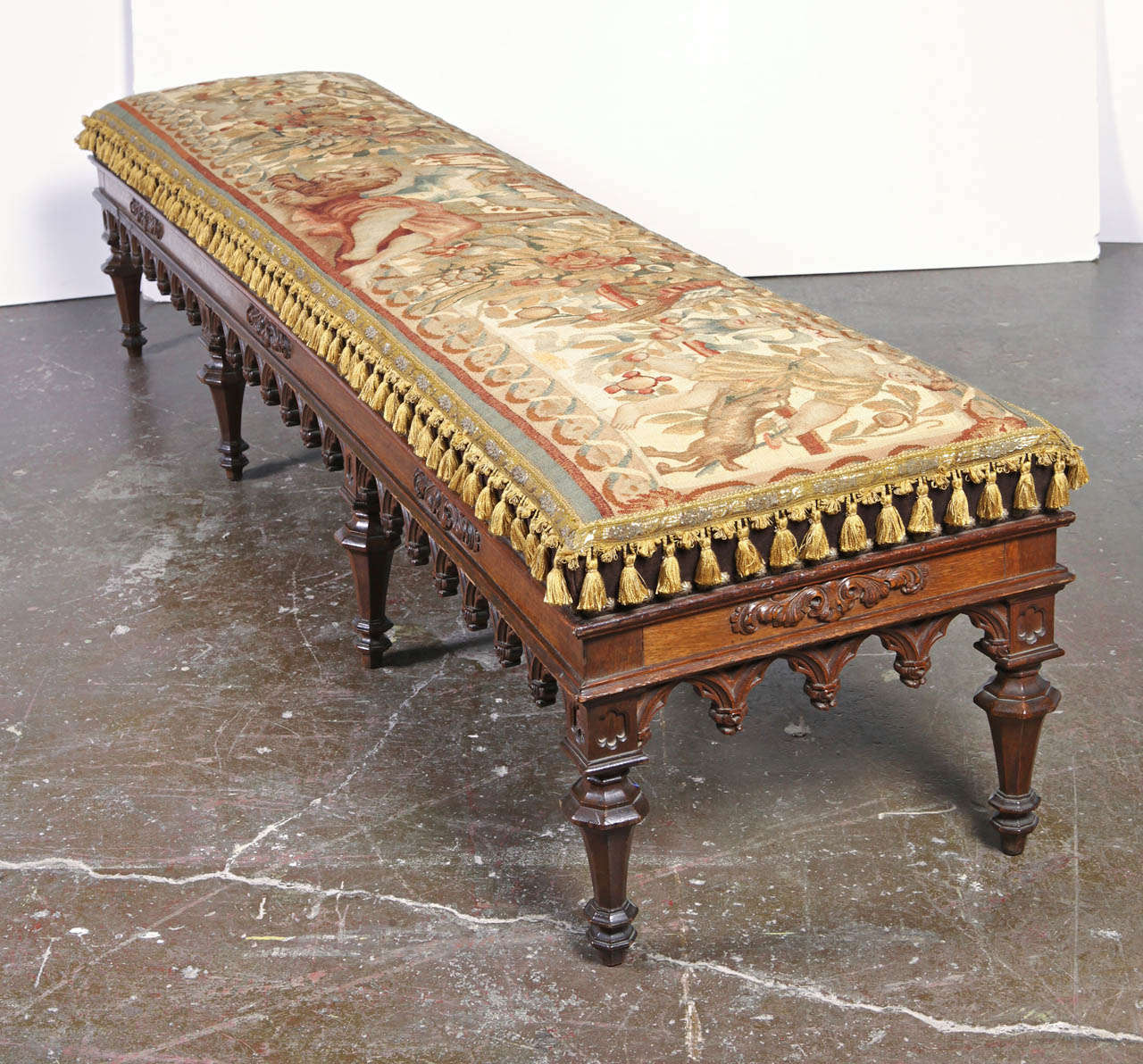 Beautifully carved 19th Century Napoleon III walnut  bench with professionally restored antique Flemish tapestry depicting  a mythological scene. Padding and springs replaced. Finished with antique trim and tassels.