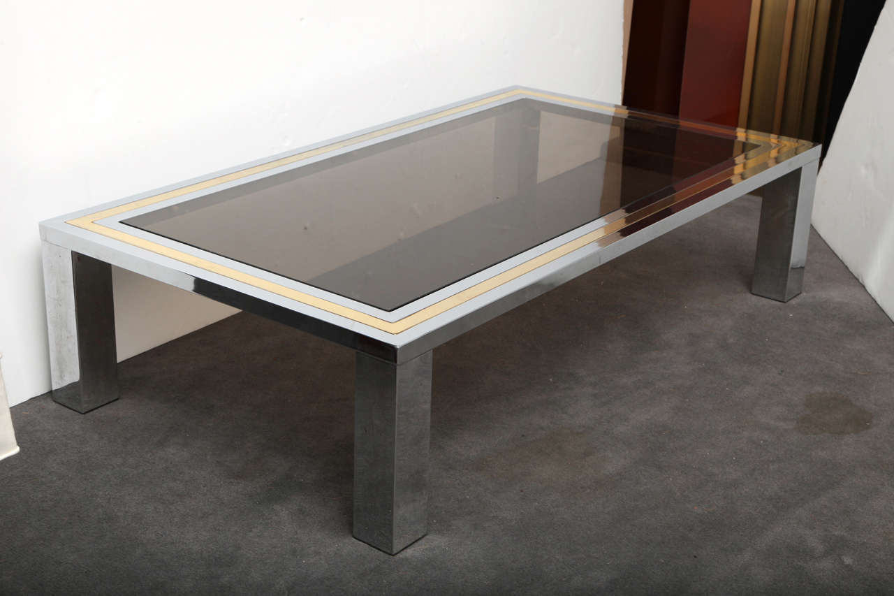 A chrome and brass coffee table with a glass top
