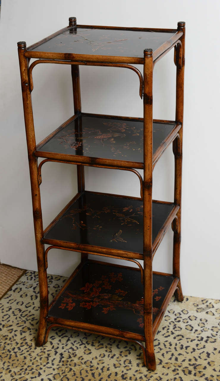 19th c. Bamboo Tiered Stand, fitted with four shelves, each inset with an ebonized panel featuring floral branch and avian patterns, joined by bamboo supports ending in splayed feet, h. 43-1/4