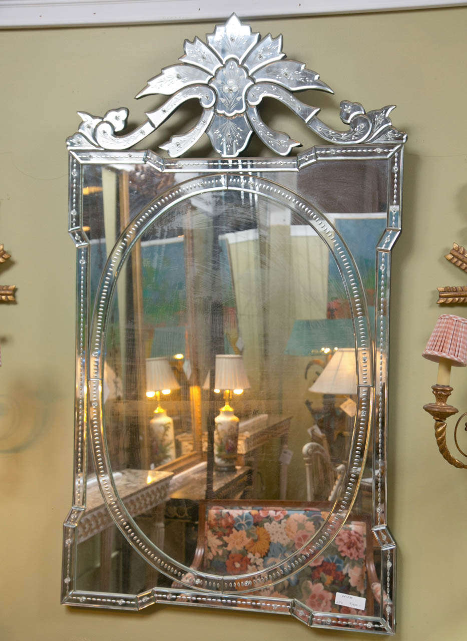 A beautiful decorative Venetian mirror, the oval plate set in a rectangular frame with etched beaded banding, the crest on top also depicting etched floral pattern.