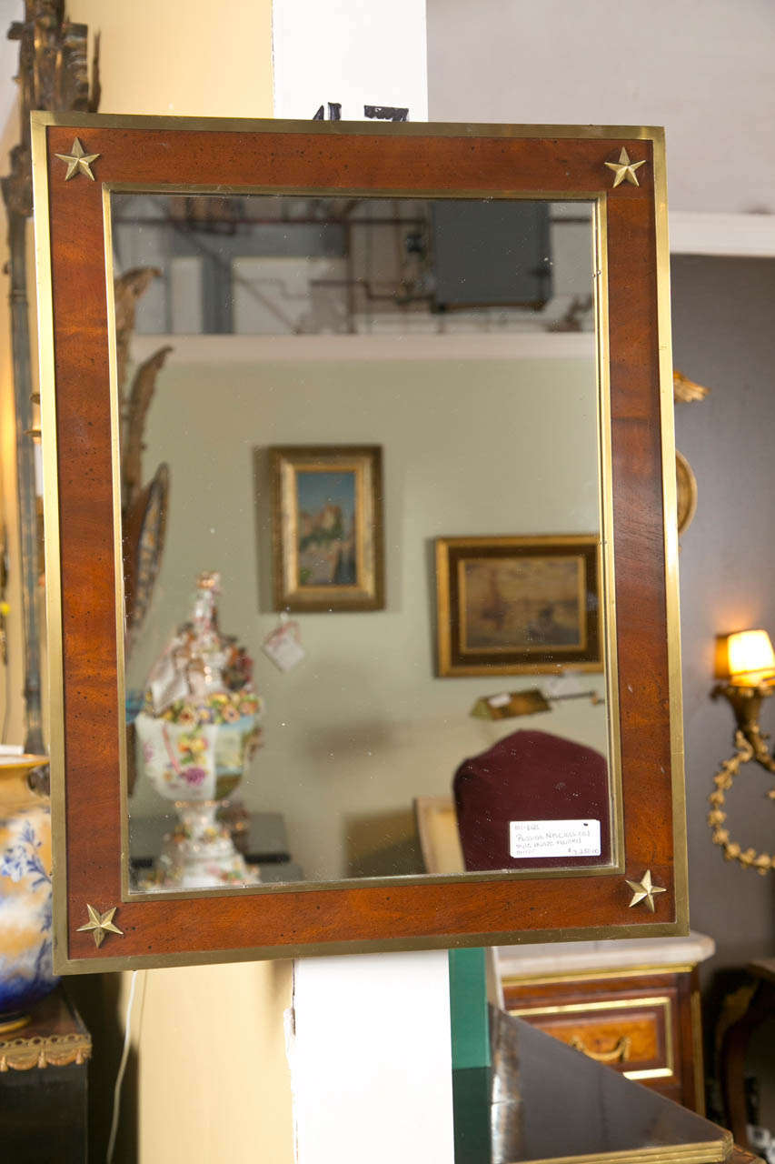 A bronze-mounted mirror in the Russian neoclassical style. The center mirror panel framed with a bronze border leading to a mahogany frame once again framed in a bronze border. The corner with bronze star design.