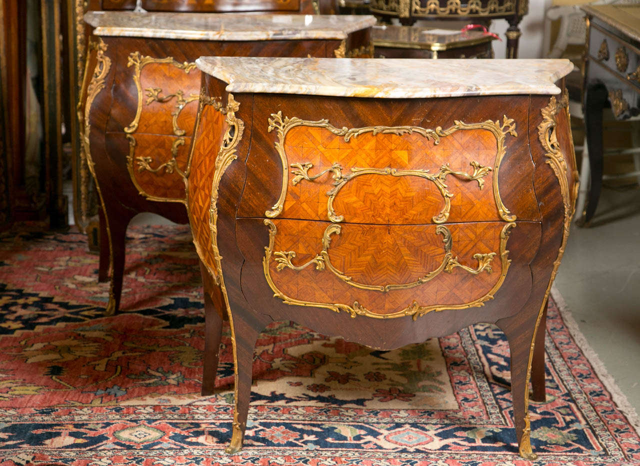A fine pair of bronze mounted French Bombe Commodes or Nightstands / sidetables.  The outer bombe casing made with Parquetry Kingswood and Satinwood veneers. Wonderful bronze framed side and fronts with two drawers each resting on full bronze