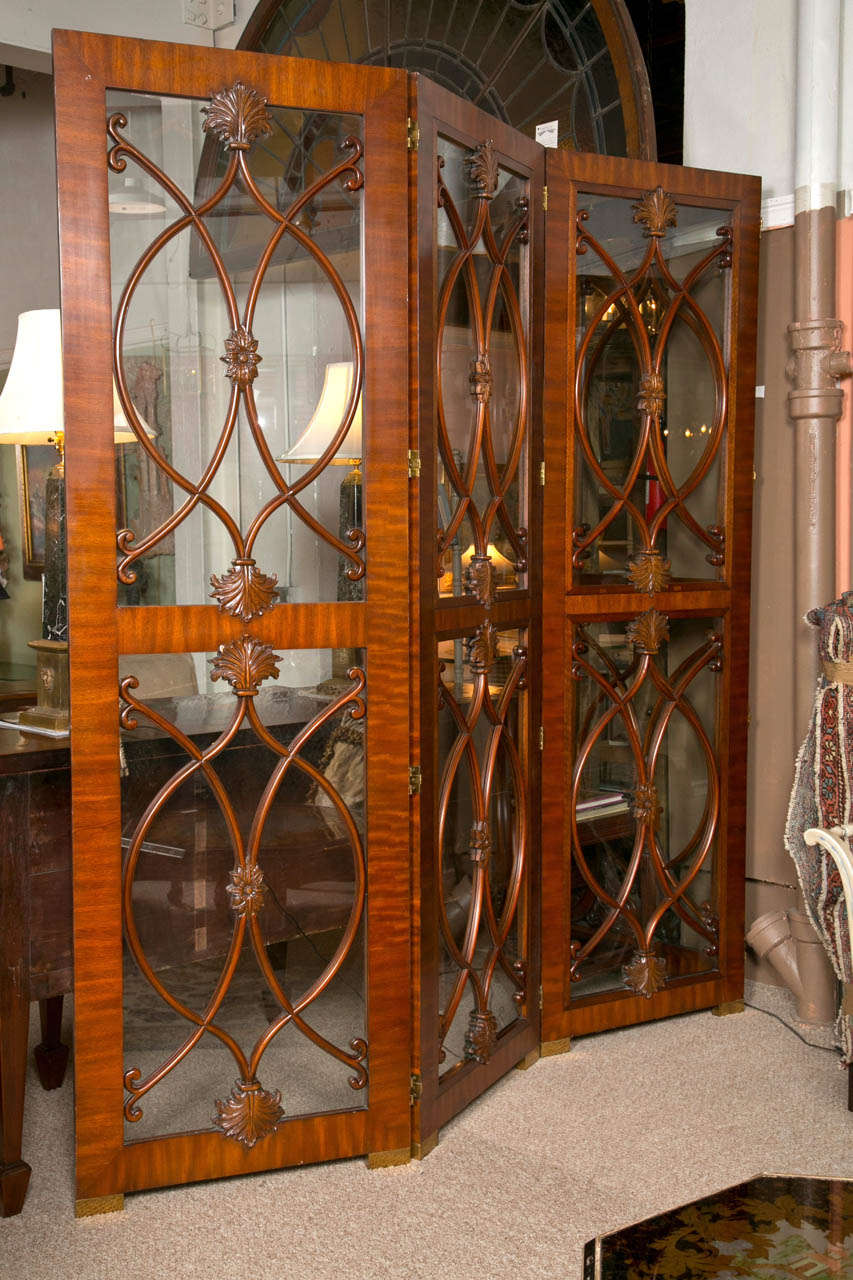 A handsome mahogany Four-panel screen, Circ 1940s in the Georgian taste, each having astragal-glazed screen with scrolled moulding, hinged in-between, raised on brass plinths. Total width is 120
