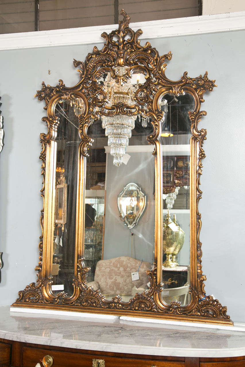 A French carved four section over the mantel / wall mirror. This highly carved Rococo mirror has all-over decorative foliage, rosettes and leaf and shell design.