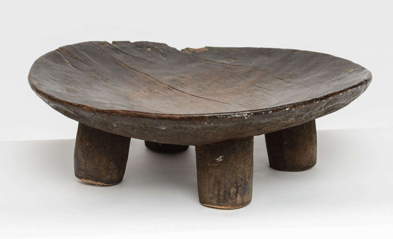 Hand-carved African wood bowl with four legs. Waxed and patinated from an earlier time and still shines. Cracks and chips add to the fantastic natural state of this solid and weighty utilitarian bowl, centerpiece, display object from West Africa.
