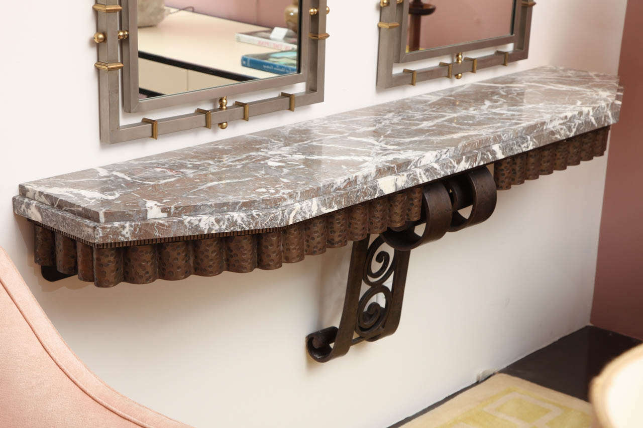 Fabulous 72" wall-mounted console table with stepped red and grey veined marble-top and wrought iron base with scrolled bracket and scalloped apron.
Art Deco in the style of Raymond Subes and Edgar Brandt.