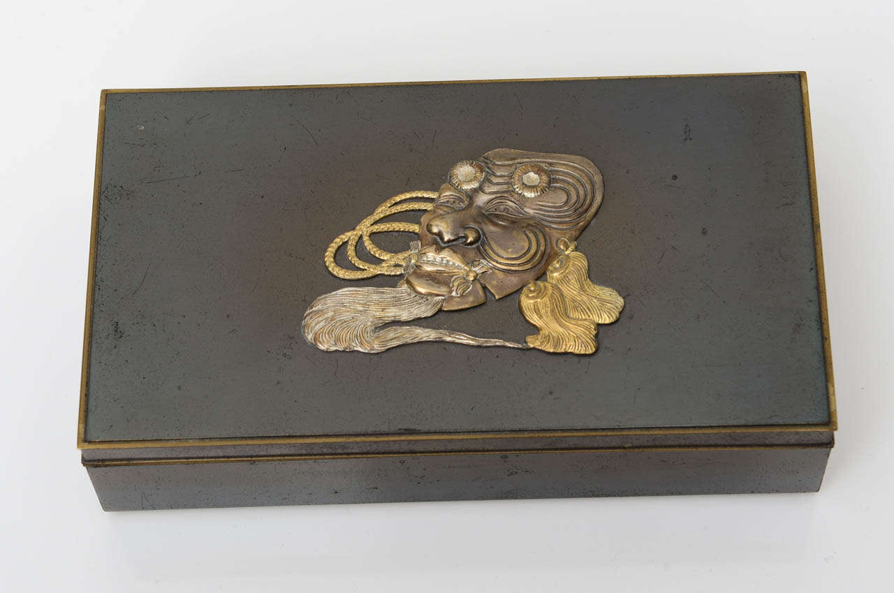 Japanese wood and mixed metal box featuring a mask motif  on the lid.