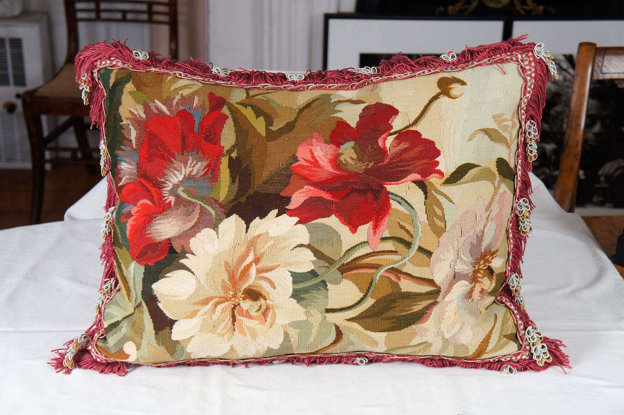 Lush deep red and pale green floral tapestry needlepoint pillow. Elaborate claret red, pale green and yellow fringed trim. Probably a piece of Aubusson carpeting. Backed in beige velvet.