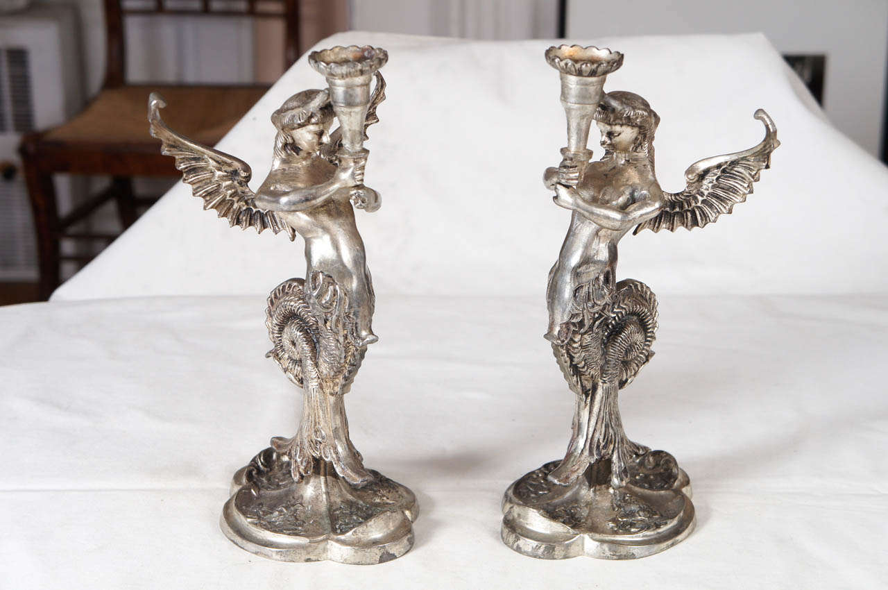 Pair of Continental silvered metal winged mermaid candlesticks, winged
and wreathed mythological figures with coiled tails holding candle receptacles on pedestal bases. Possibly German made.
