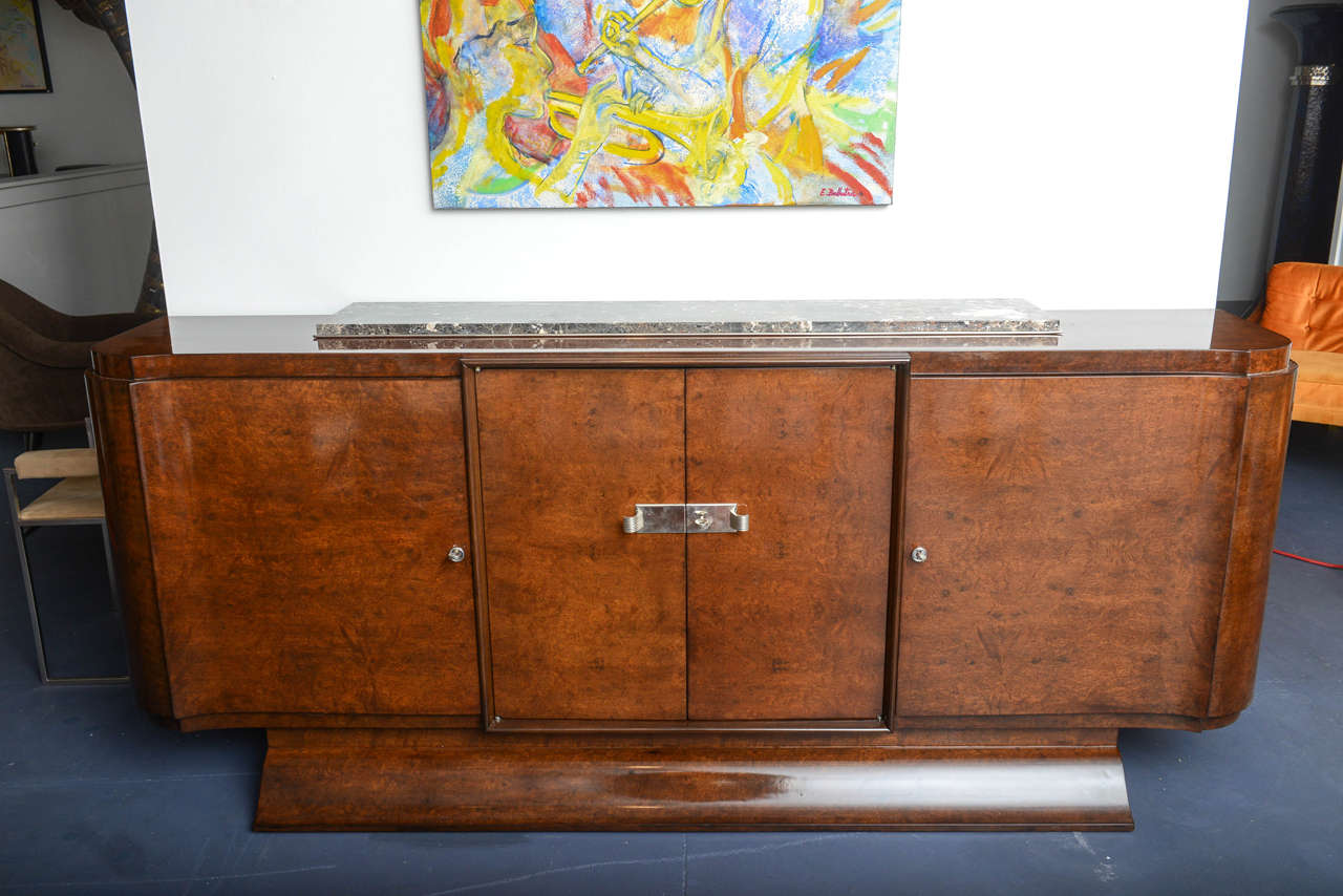 Elegant burl of Amboina French Art Deco sideboard.
Front part movement in a delicate curved line.
Inside in light wood with shelves and a pair of drawers in the upper middle part.
The top is ornamented with a narrow piece of marble which give to