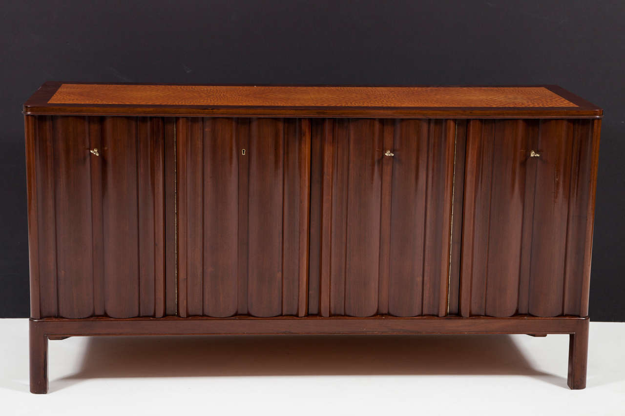 An exceptionally high quality Frits Henningsen sideboard in mahogany, birch, elmroot and maple, circa 1930s, the rectangular top with a flamed birch inlaid top above four solid mahogany waved doors enclosing shelves and drawers. The drawer fronts of