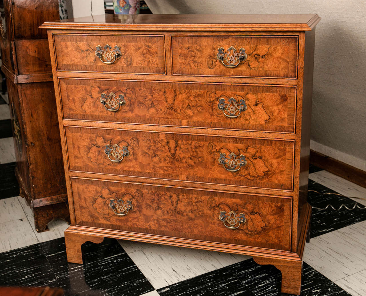 Created by our English cabinetmaker with exacting detail, this Georgian styled walnut burl chest has the traditional arrangement of two drawers over three graduated drawers, each crossbanded in straight grain walnut and mounted with brass bail