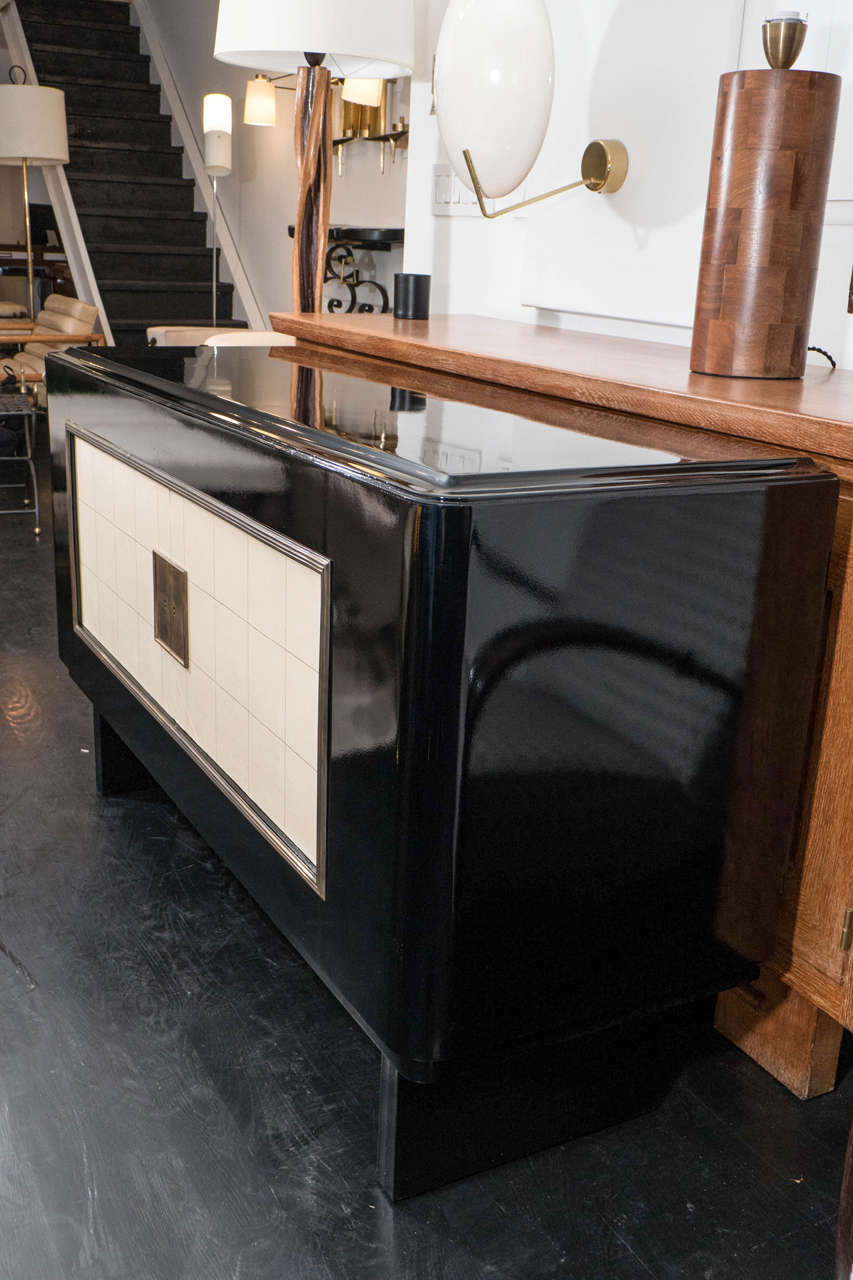 Black lacquered sideboard with gilt detailed parchment doors in the manner of Jacques Adnet. It is detailed in brass with one interior shelf.