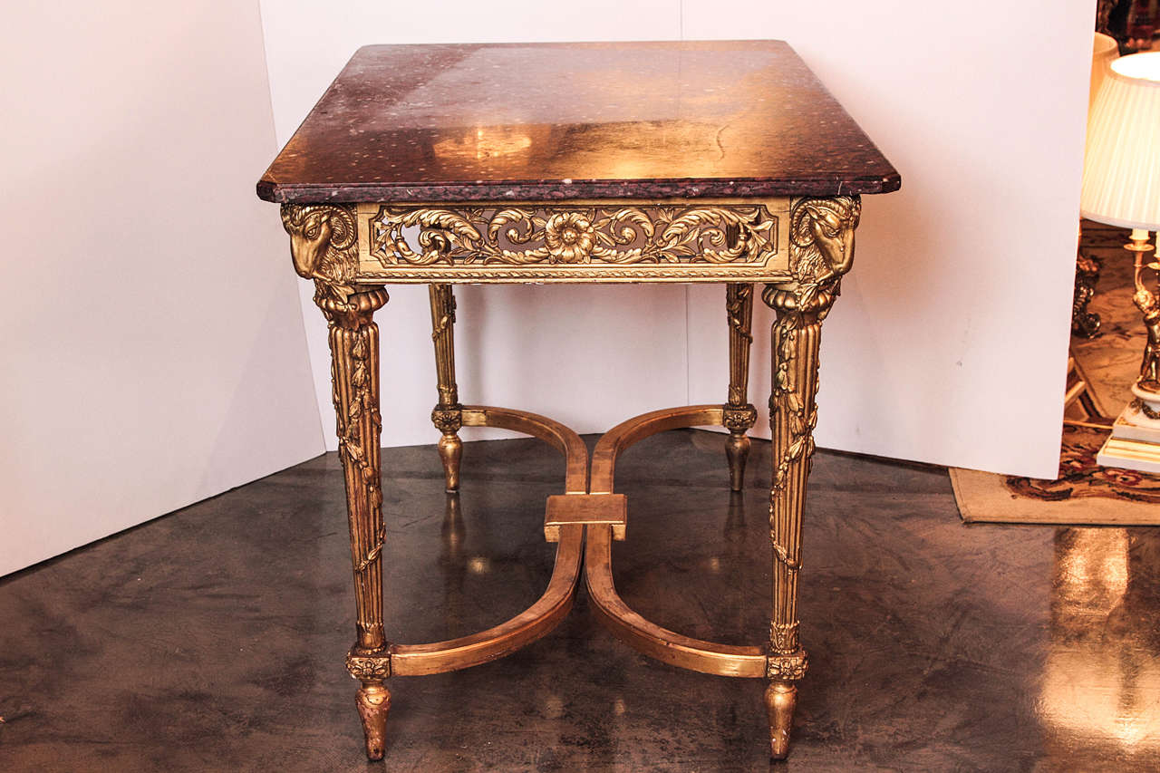 19th century beautifully carved French gilded center table or console. Carving beautifully detailed on all four sides this table has the original red marble top and a bottom stretcher