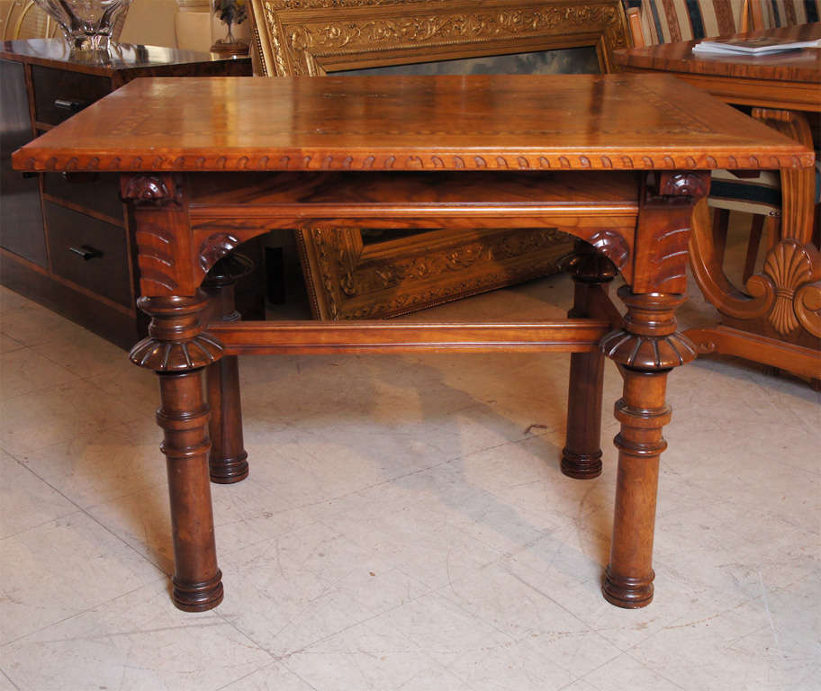 Renaissance Revival style small library table or game table in walnut with turned and carved legs, gadrooned edges and inlaid marquetry top.