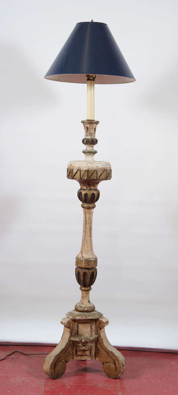 Originally antique Italian alter candlesticks, the pair have been transformed into up-to-date floor lamps, electrified for USA use. They are decorated in gilt, as well as green and white paint and each sits on three volute legs interspersed with