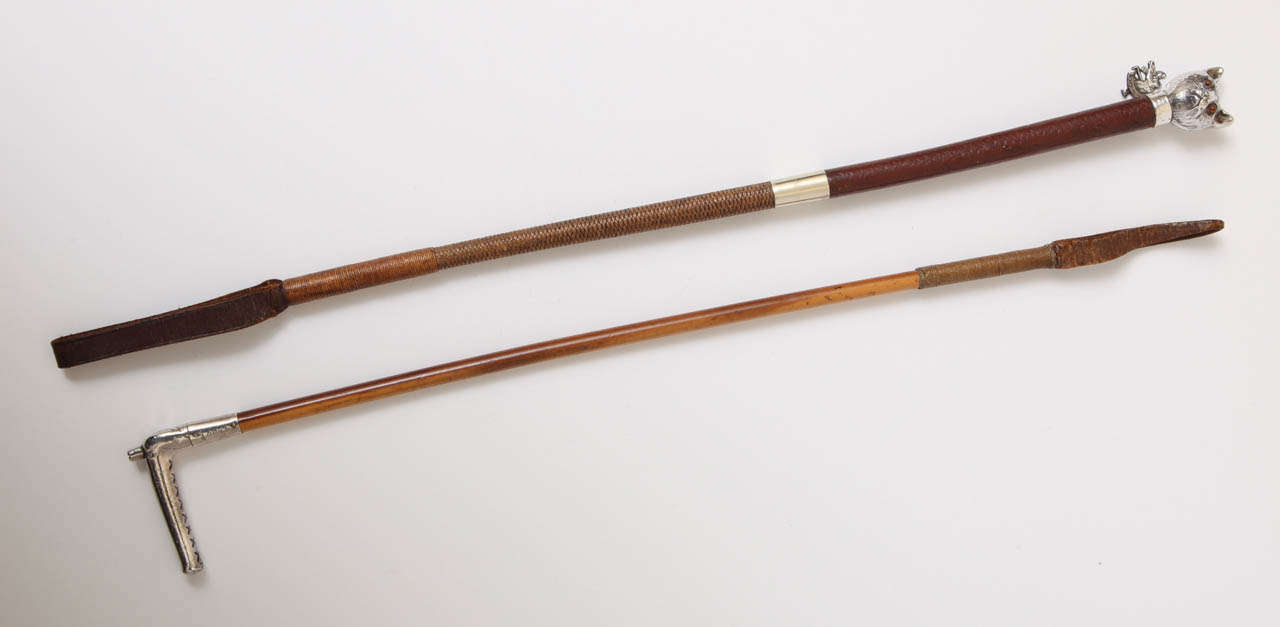 A pair of riding crops/whips . The first is an unusual and very high quality riding crop which is adorned with a superbly rendered cat's head. Highly engraved and detailed, the cat's eyes are made of glass which has been hand painted and he has an