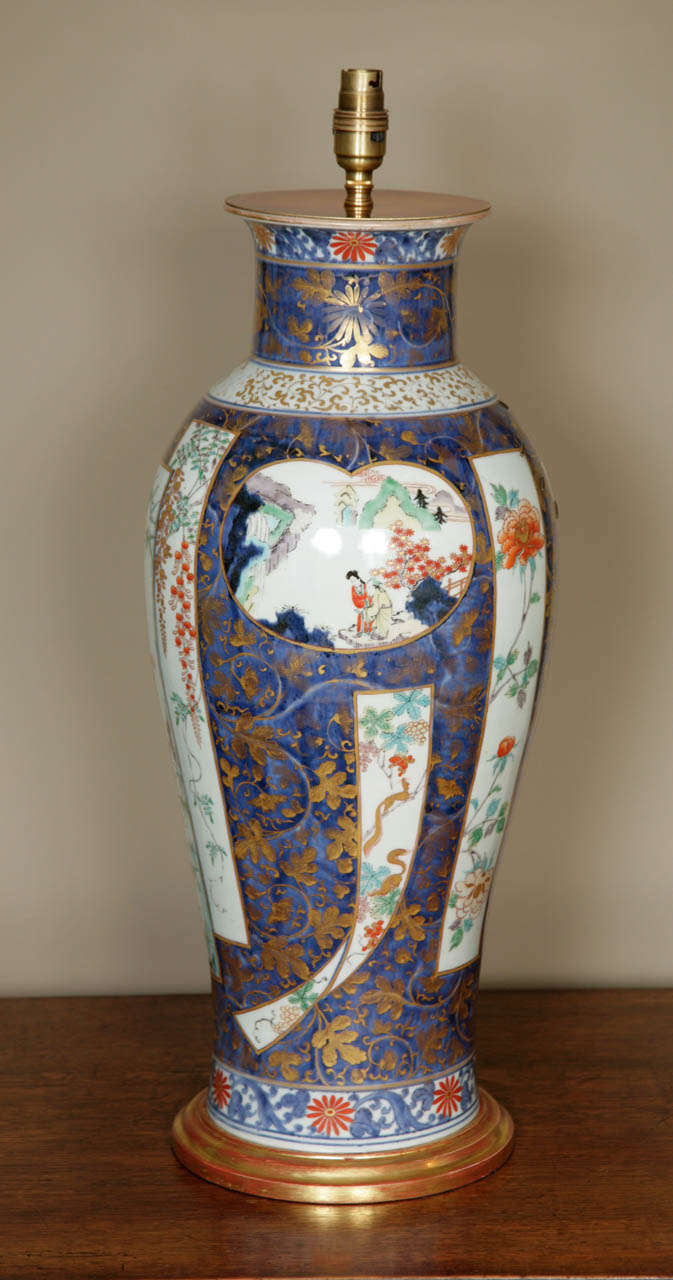 A large lamped Japanese late 17th / early 18th century Imari Vase of elongated ovoid form with flaring neck, decorated in the Imari palette of underglaze blue with overglaze iron-red and green enamel with details in gold. The decoration with scroll