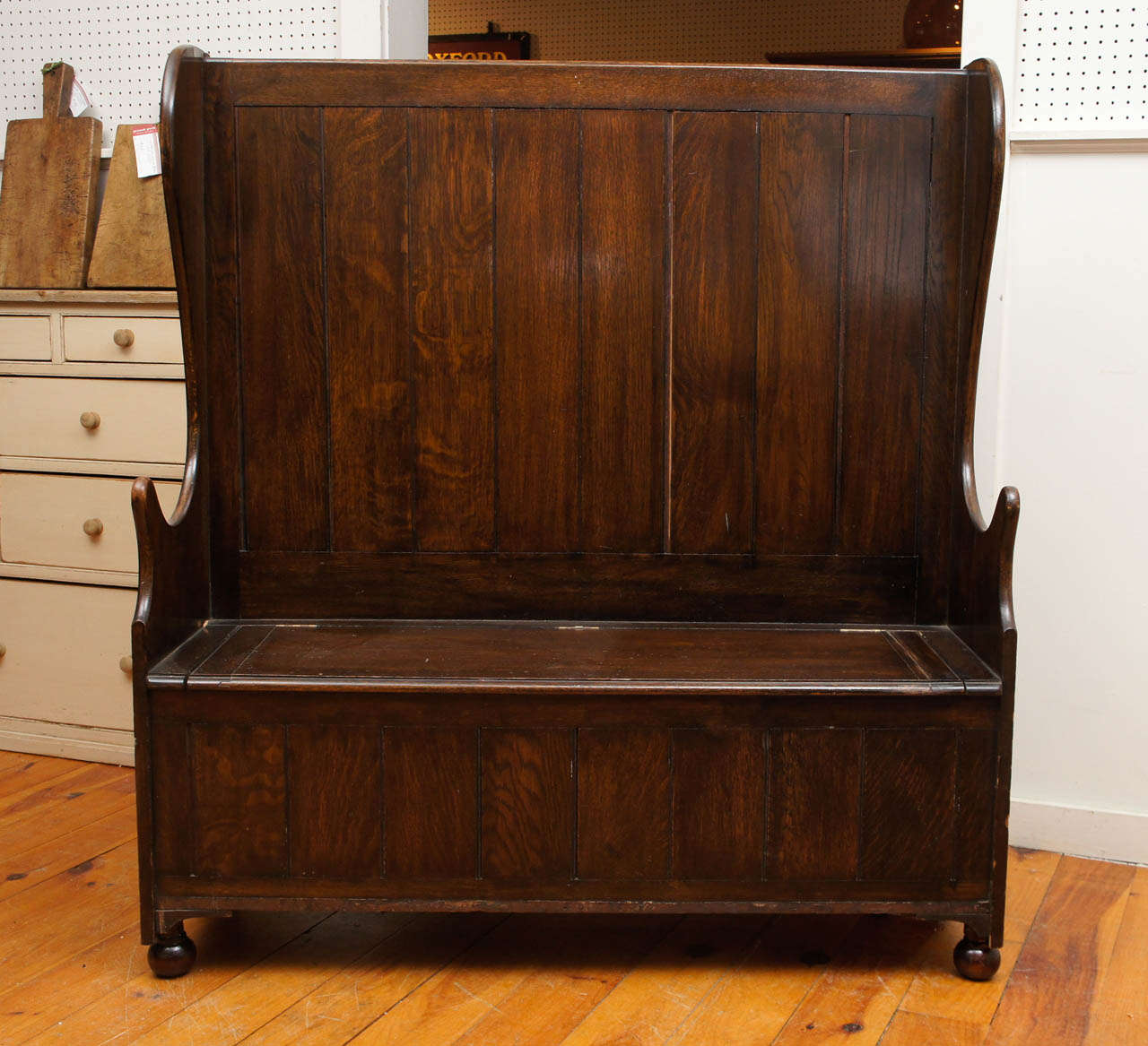 Tall dark and very handsome is the perfect way to describe this wonderful oak box seat settle. Its high back caught the warm heat of the fire in an English pub around 1860. The sides are gracefully curved as well as the arms. The seat lifts to a