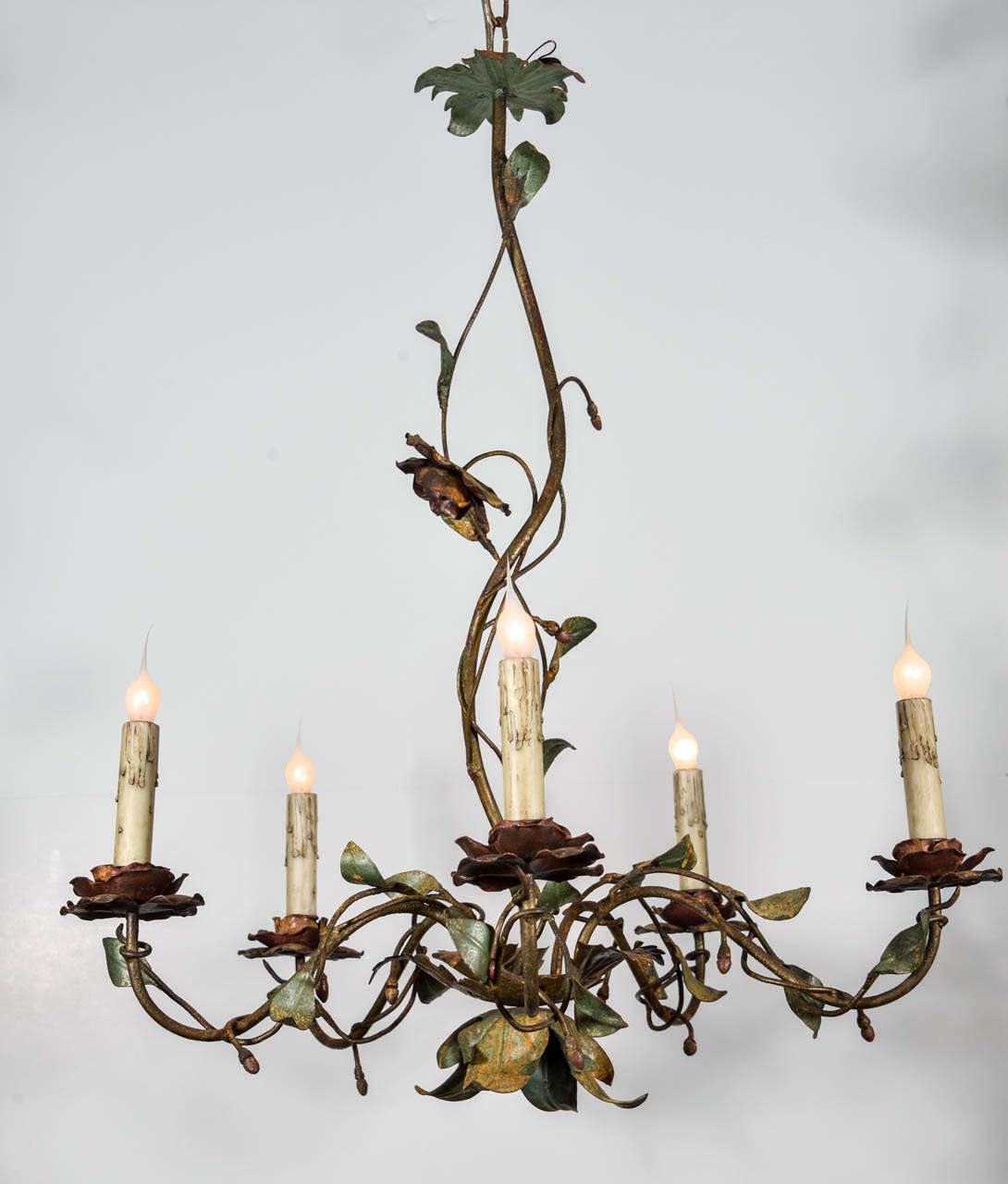 Vintage tole chandelier with floral motif featuring elegantly time-worn painted and gilt details and a beautiful patina. Newly-wired with five gracefully curved arms supporting flower-shape bobeches, four feet of additional chain and a simple canopy.