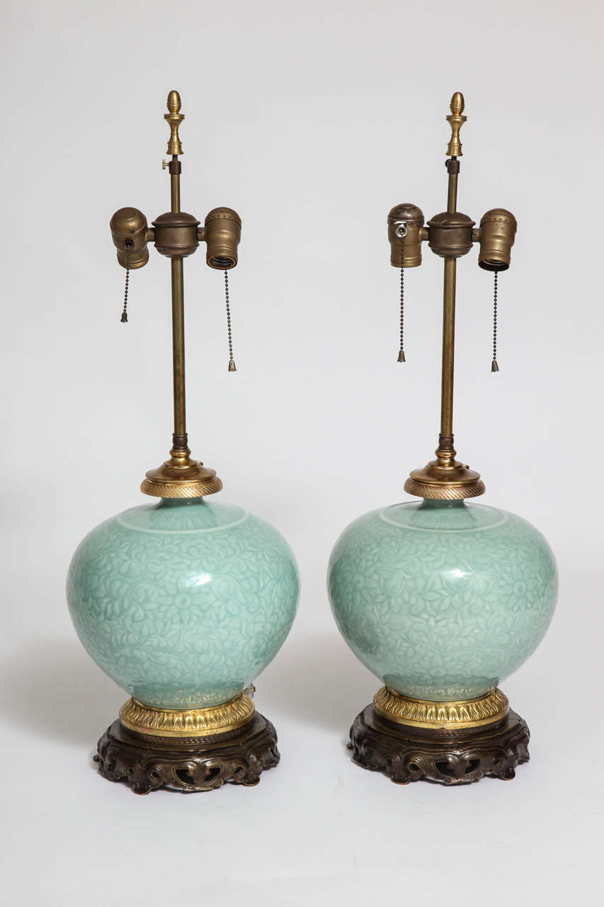Pair of Chinese Celadon Porcelain and Ormolu Mounted Vases Mounted as Lamps on Chinese Carved Wood Bases. The Celadon porcelain is incised and engraved with Islamic floral motifs. 19th century or earlier. 

Dimensions 
Height with Electric