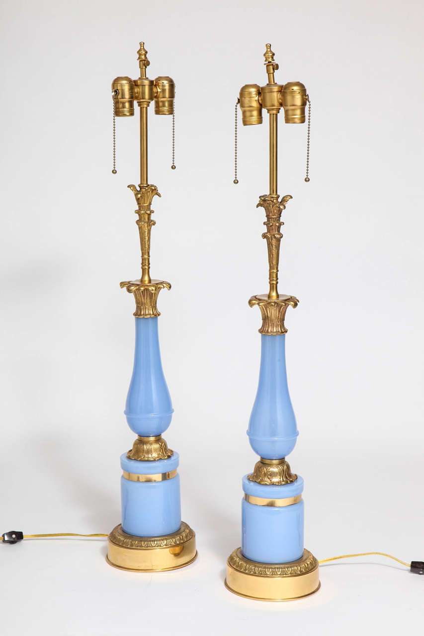 Paire de lampes anciennes en bronze doré et opaline bleue, 2e moitié des années 1800. Au sommet de l'Opaline bleue se trouvent des acanthes en bronze doré, inspirées du sommet d'une colonne corinthienne, qui renforcent l'impression de style