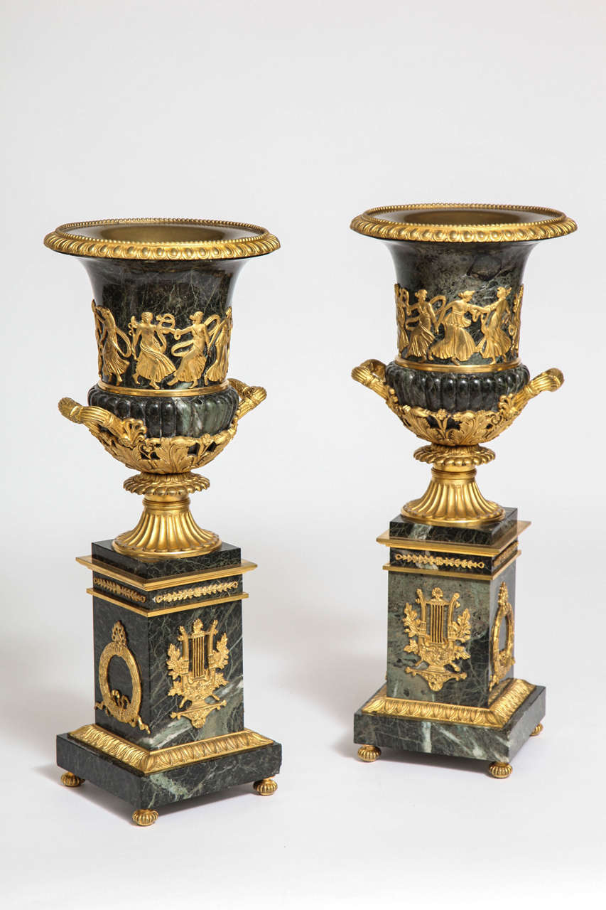 Pair of antique French neoclassical or Empire Verde Antico marble and ormolu-mounted campagna-form urns. The base is decorated with two-toned ormolu matte and burnished 24-karat gold garlands and emblems depicting the lyre a classical musical