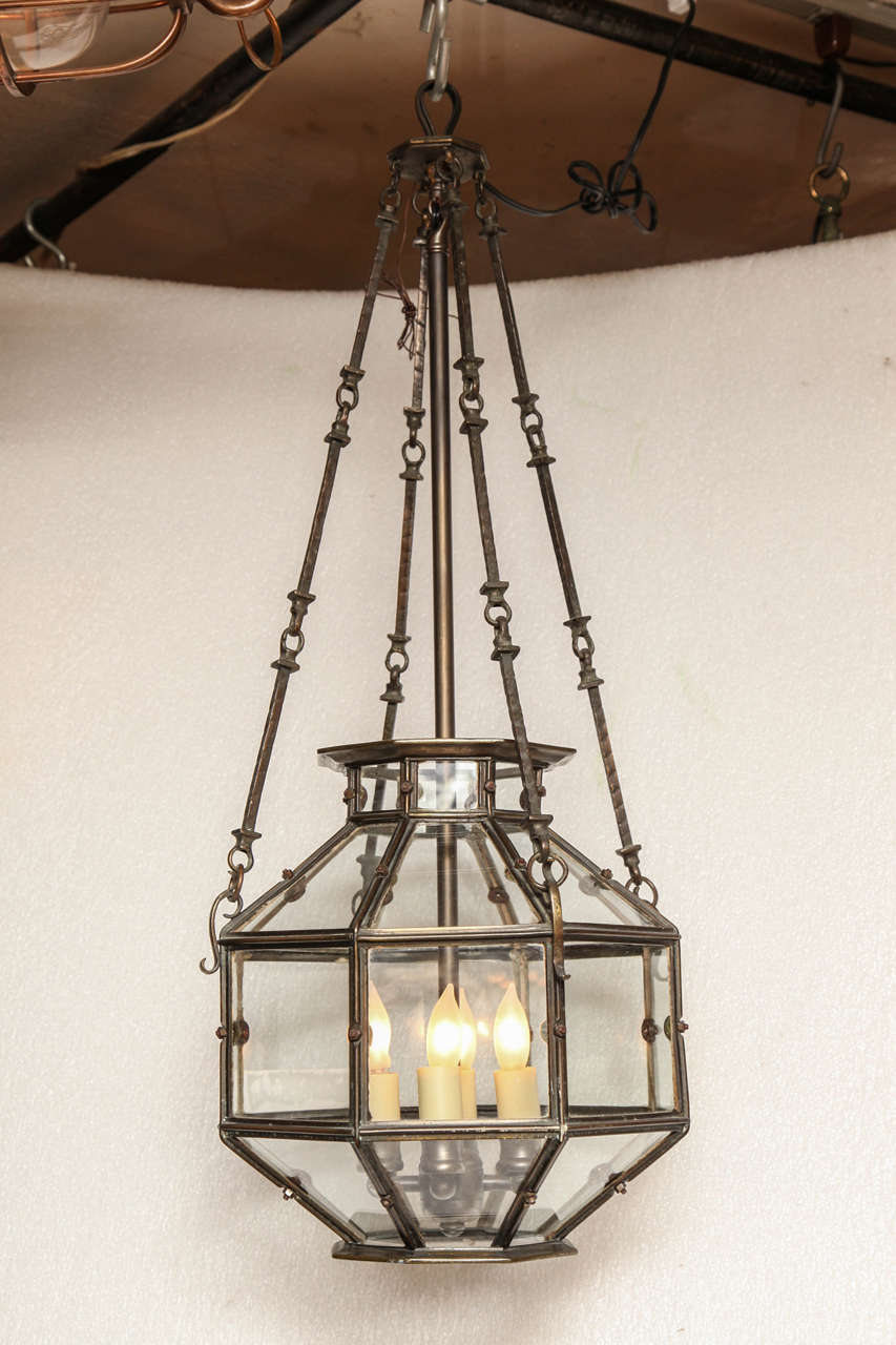 A glass lantern with unique glass paneling and custom made cluster matching the original finish of the light's metal. Hanging from original chain it was made with in the 19th C.

Handpicked by buyers at Ann-Morris, Inc.