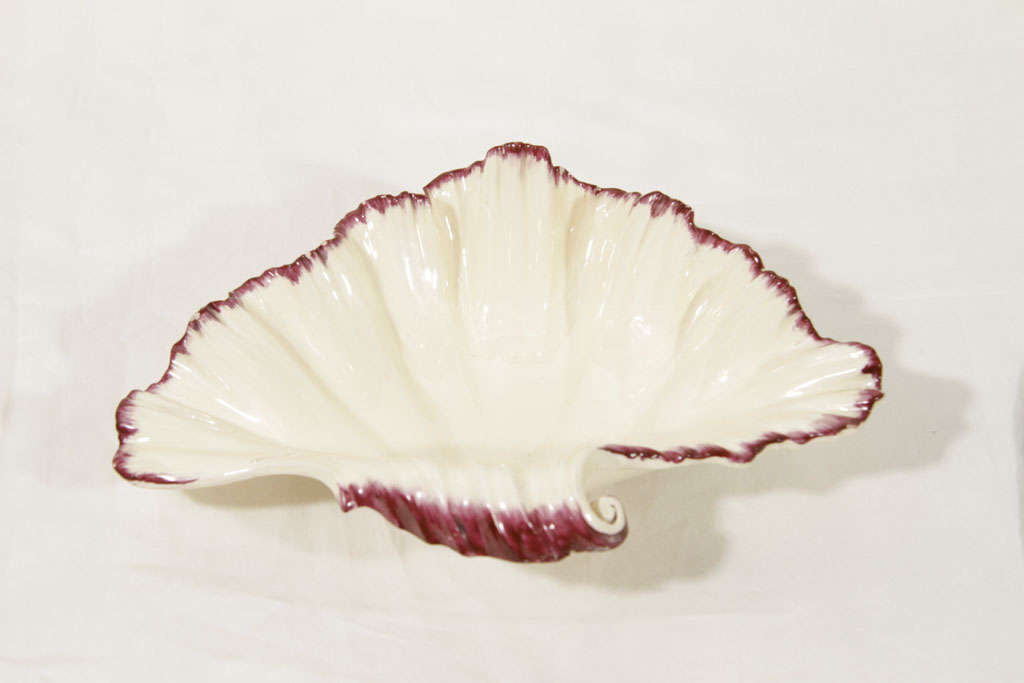 This Wedgwood creamware shell shaped dish is naturalistically modeled as an oyster shell and has a painted crimson colored shell edge. Shell edge bordering made its first appearance at Wedgwood during the summer of 1776.*<br />
During 1778 and