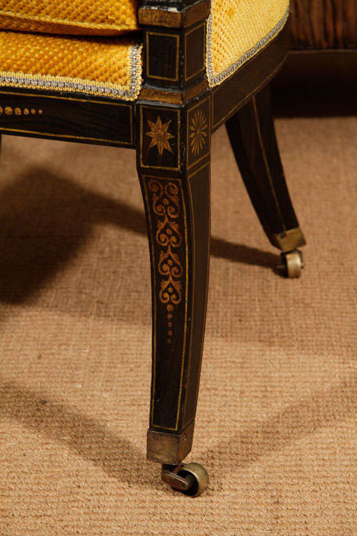The gondola backs with a gilt neo-classical design incorporating a center urn flanked by griffins with trailing rinceau. The backs on s-scroll arm supports. The chair seat rails with painted gilt patarae and anthemion decoration. The chairs's front