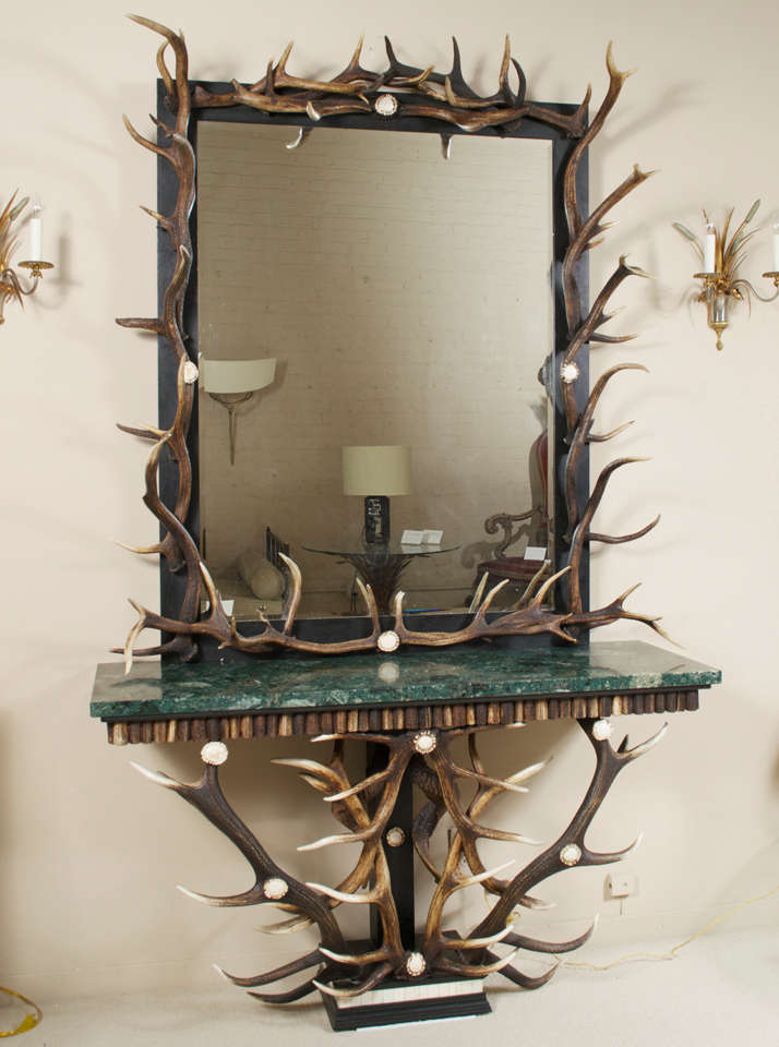 An exceptional marble-top console with a tapering base of interlocking stag-antlers,  bone parquetry and ebonized wood.
The matching, massive, beveled mirror has a black painted frame, enclosed by interlocking antlers.
Anthony REDMILE (20th