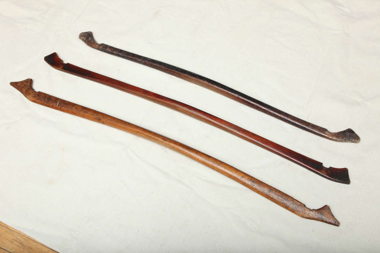A set of three wooden Chinese handcarved shoulder yokes for carrying goods or water. Used throughout China, these custom fabricated sticks show the wear and tear from the ropes that cut into the wood after years of back breaking labor. original