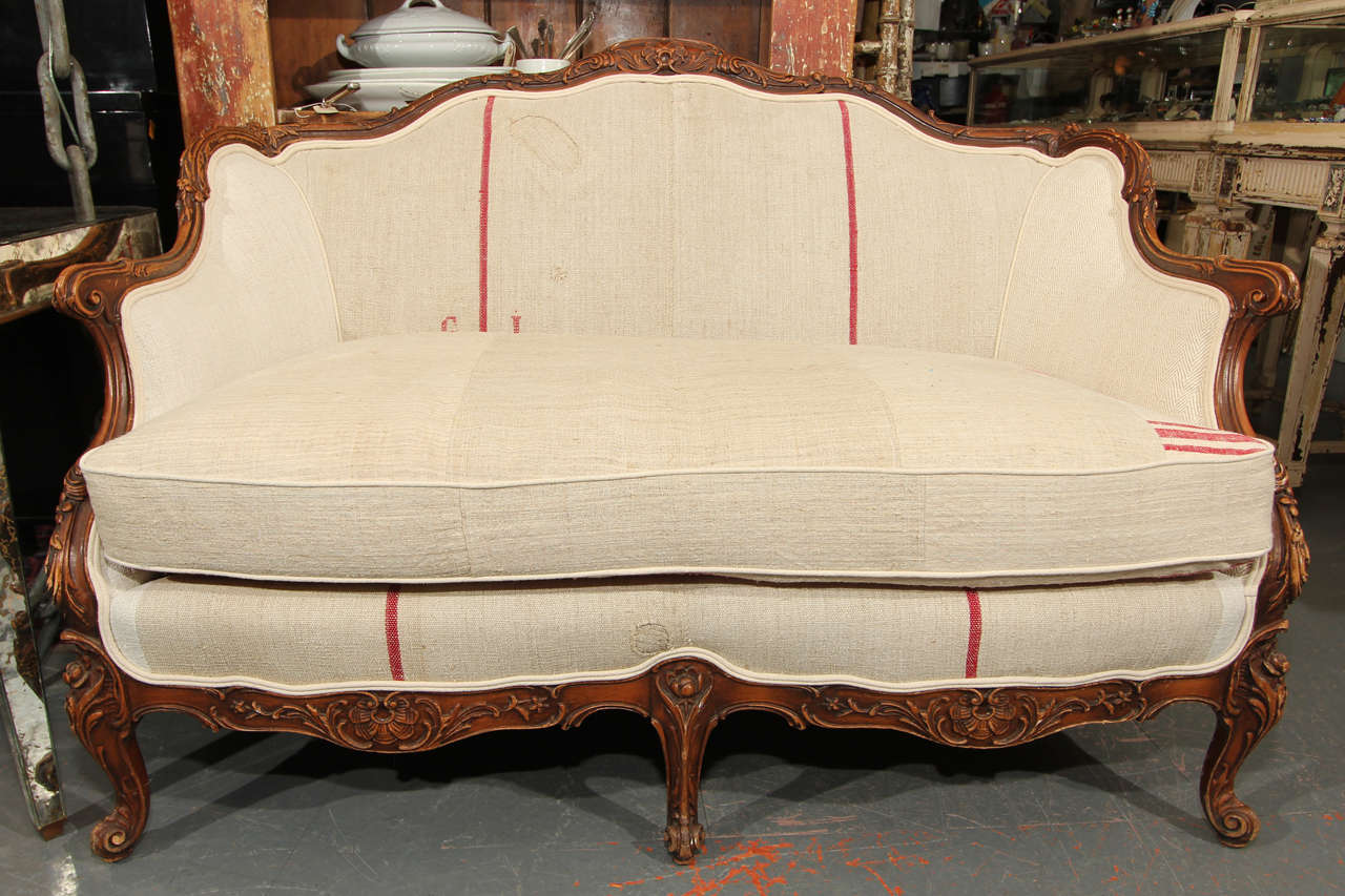 Nice small-scale French setee reupholstered in heavy linen and grainsacks featuring original repairs to fabric. Down wrapped cushion reverses to horizontal red stripe.