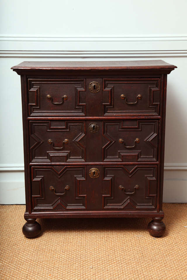 A Charles II geometric fronted oak chest with panel sides and molded top over three drawers sanding on ball feet.  Diminutive proportions, probably used as a child's chest.  English, circa 1690.