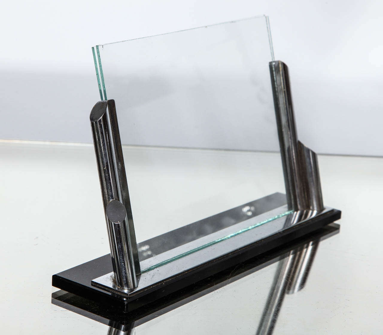 A great Art Deco streamline picture frame with a sandwich of glass held in place by a streamlined nickel plated frame on a black glass base