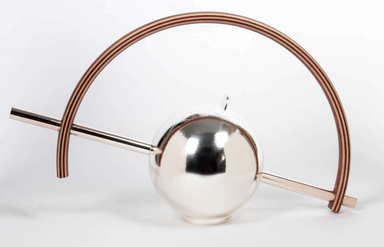 WOLFGANG GESSL (b. 1949)  Austria / Sweden 

Teapot    1990

Hand wrought and hand hammered spherical silver teapot with cylindrical handle and spout elements, maple and padouk wood layered arching handle

This is No. 2 out of the edition of 3