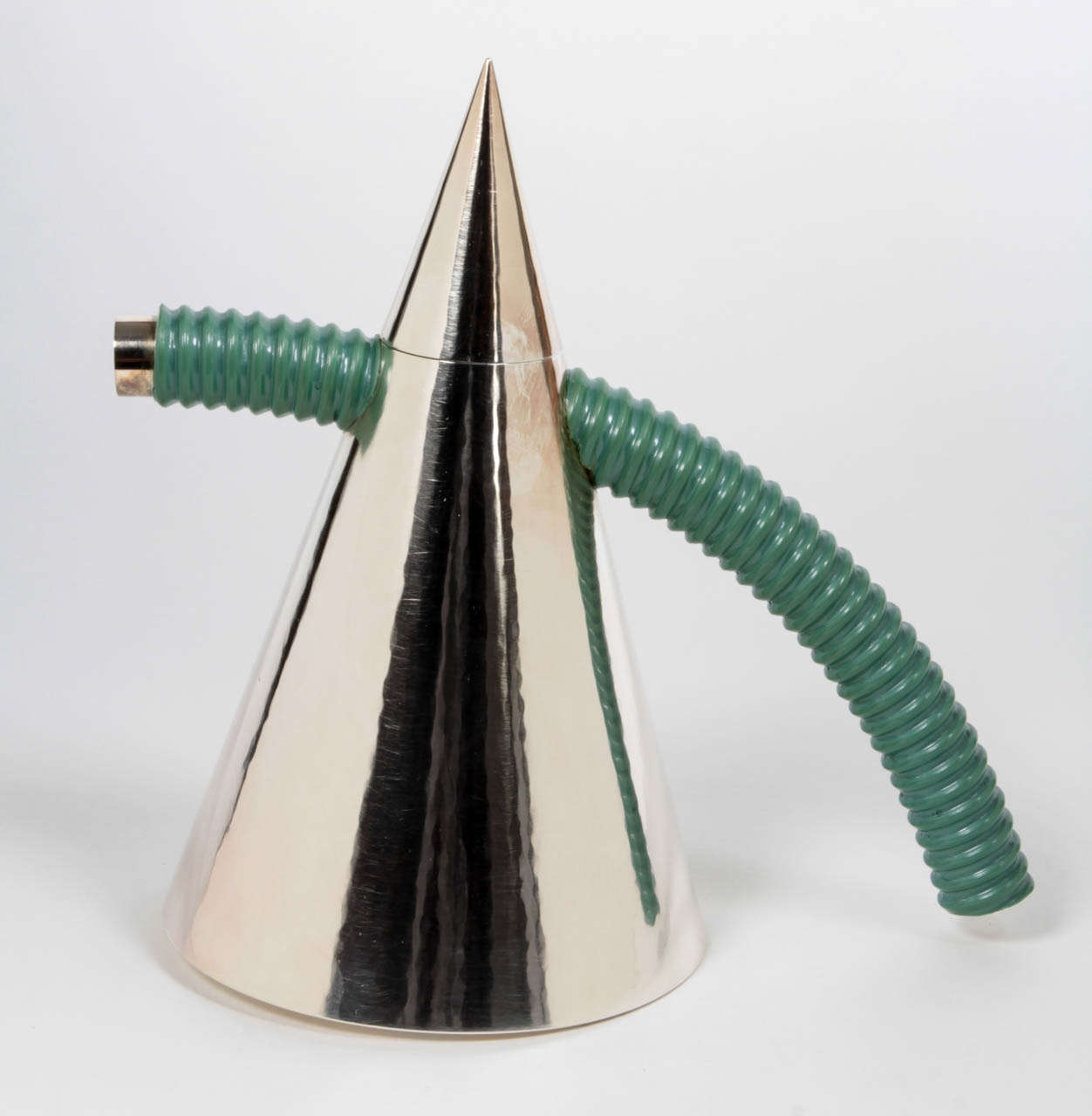 WOLFGANG GESSL (b. 1949)  Austria / Sweden

Covered pitcher   1996 (designed 1995)

Hand wrought and hand hammered silver cone shaped covered pitcher form with a green PVC handle and spout over silver cylindrical arching forms

Marks: Wolfgang