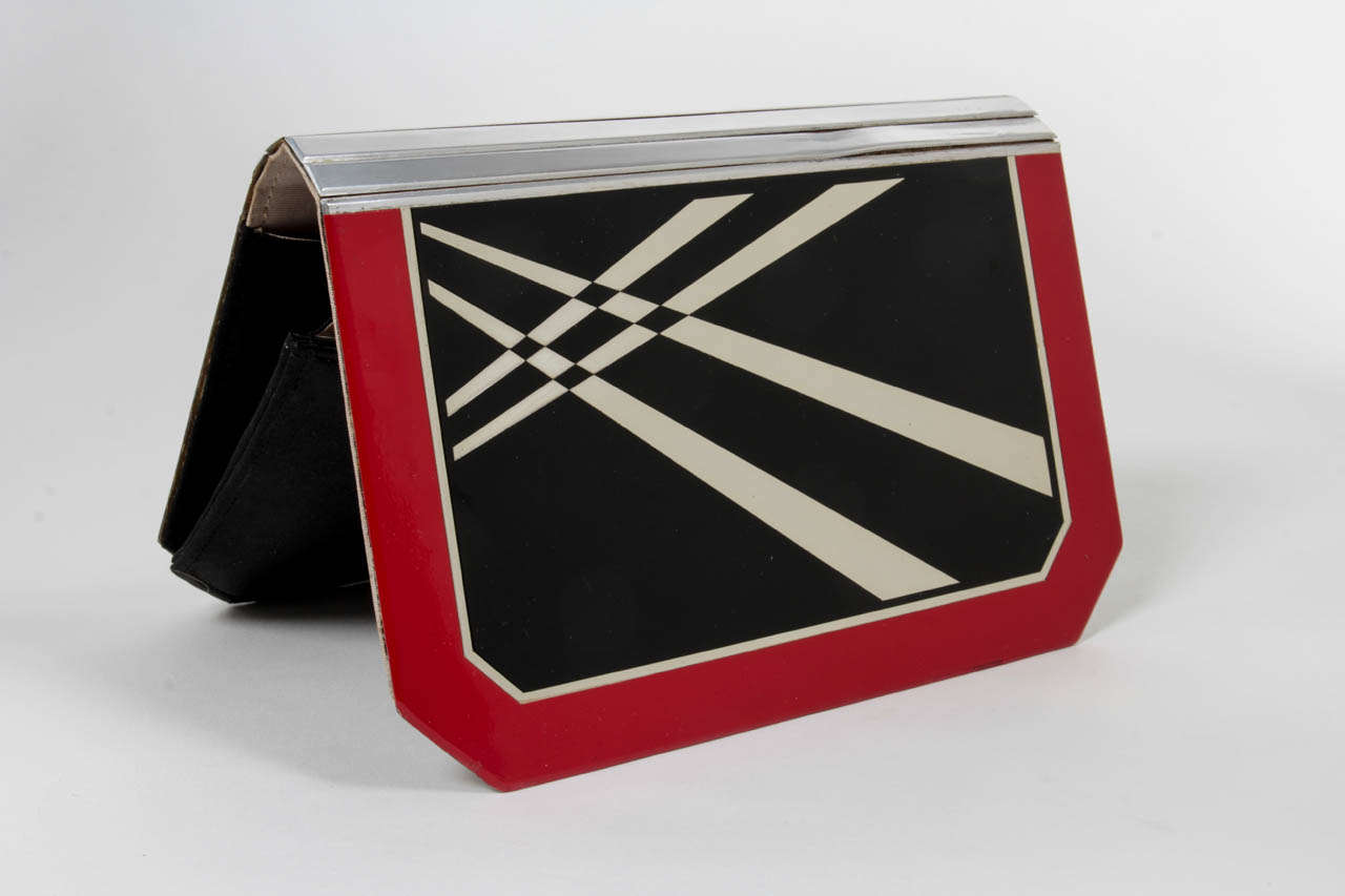 FRENCH ART DECO

Clutch / purse c. 1930

Black and red lacquered aluminum with a geometric design with a black silk satin and gray moire interior. Original coin purse, cardcase and mirror

Fabric label on inside: Made in France