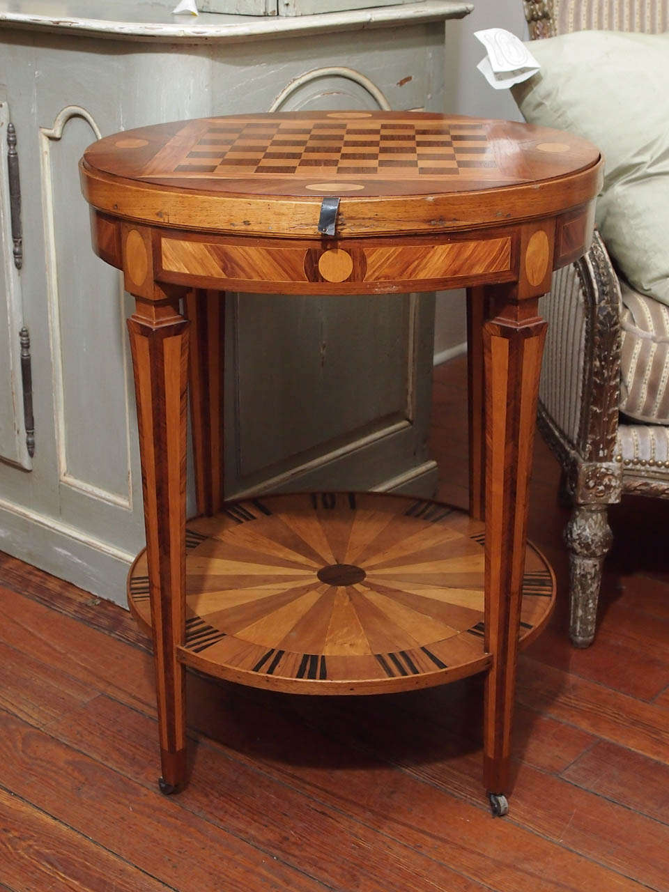 19th century game table with inlaid marquetry. The top is a chess game board and comes out. Under is a green velvet top for playing cards. The table has one drawer and the legs are on brass wheels.