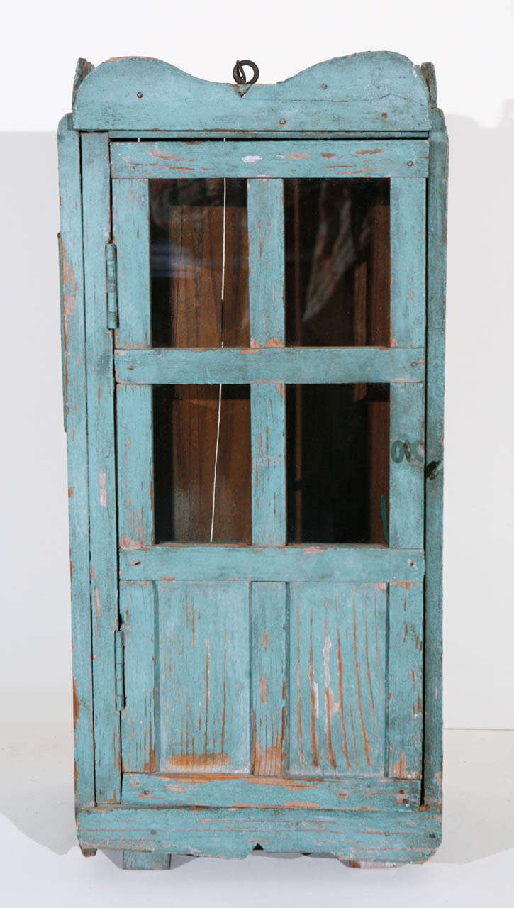 Antique wood cabinet with wood and glazed hinged door. Painted in original old blue paint with period glass. Possibly used as a niche for a Santos (religious figurine).