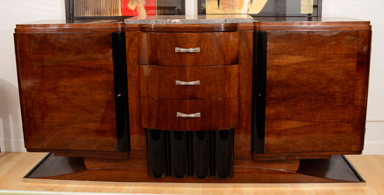 Walnut buffet with grey marble-top and black lacquered accents.
Three drawers with polished chrome hardware. Two large doors reveal two shelves.